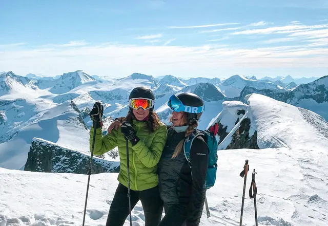 Two skiers on a mountain peak with panoramic views