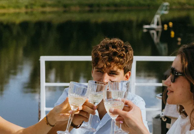 Friends toasting by a lake in the afternoon sun