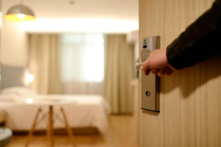 A guest unlocking an apartment door with a key